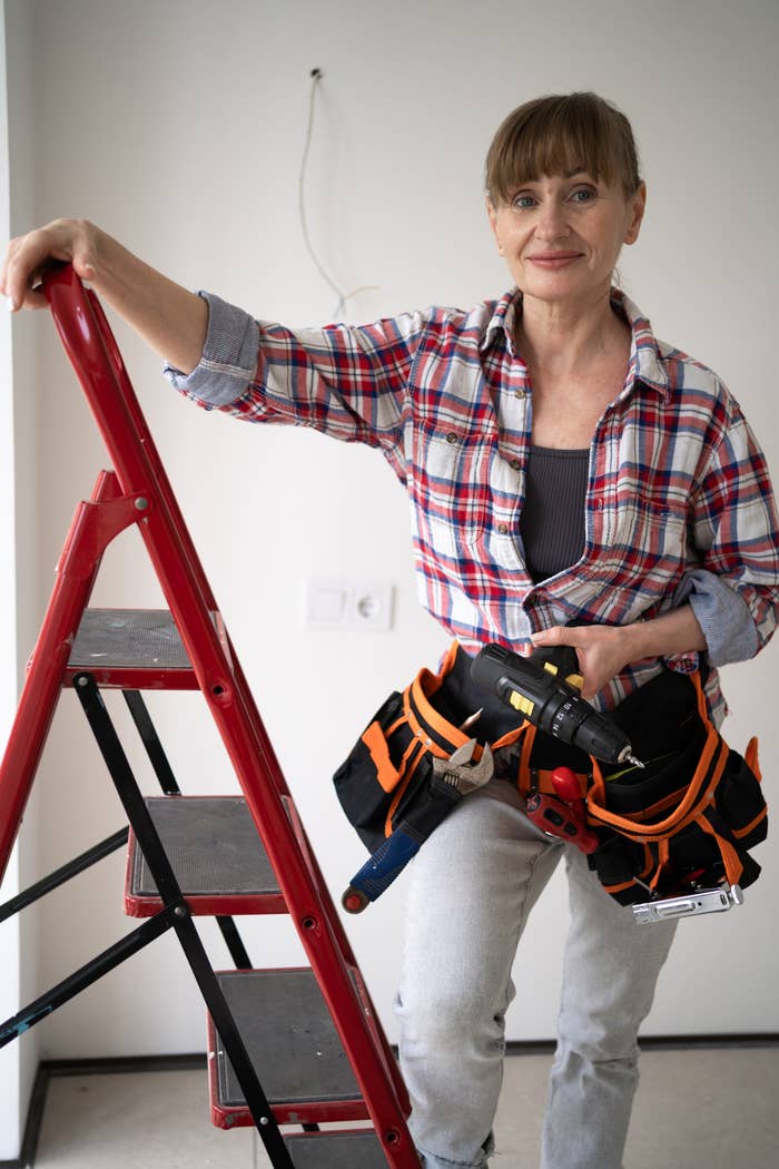 Person successful  a plaid garment  holding a instrumentality   belt, lasting  adjacent  to a ladder successful  a country   nether  renovation