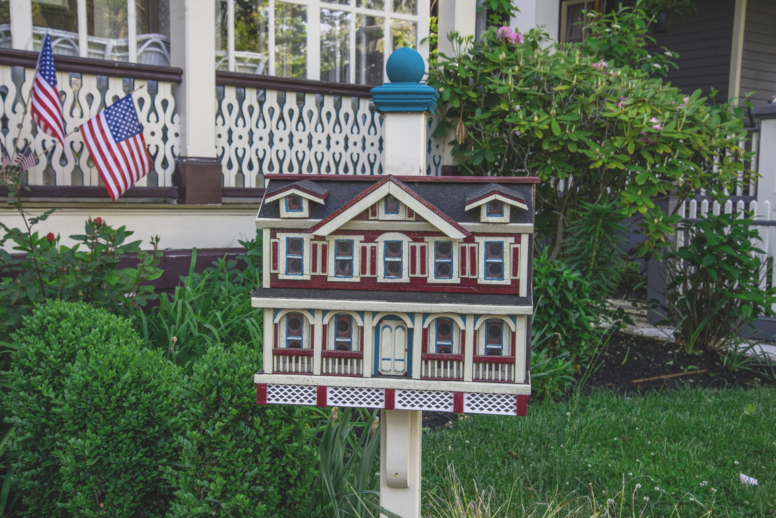 Miniature location   mailbox successful  beforehand   of a structure  with 2  American flags, surrounded by greenery and shrubs