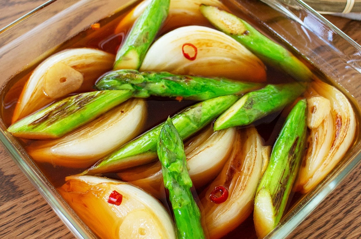 アスパラガスと玉ねぎが醤油風味のソースでマリネされた料理。