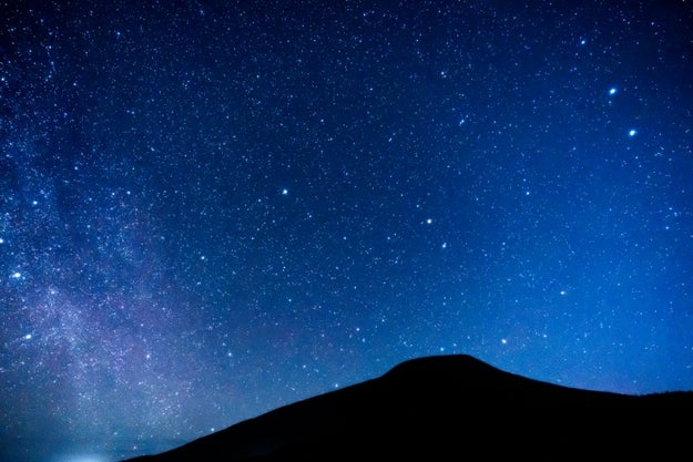 星空の下に広がる丘のシルエット。たくさんの星が夜空に輝いている。