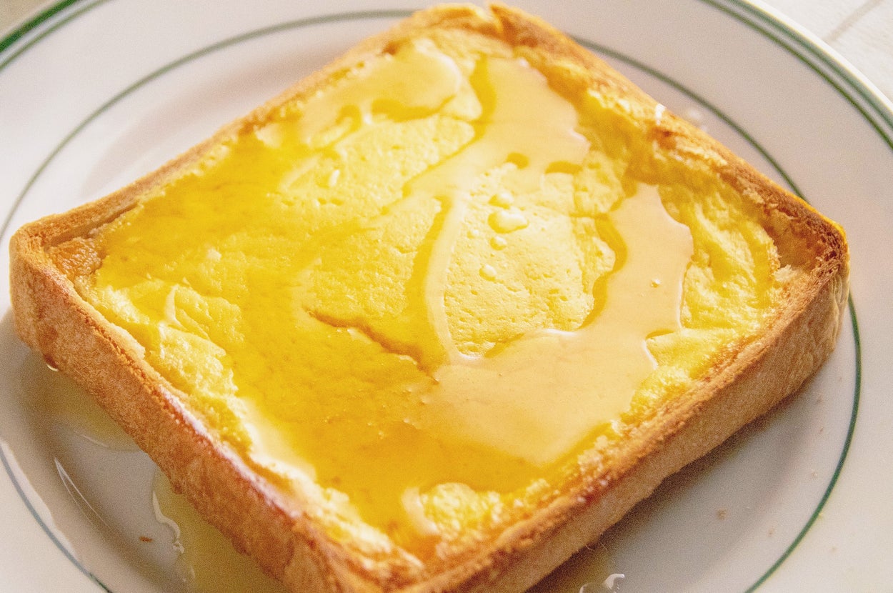 トーストに溶けたバターと蜂蜜がかけられている朝食のお皿。インテリアにも合ったシンプルなプレゼンテーション。