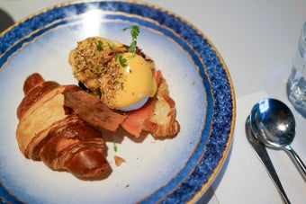 クロワッサンとエッグベネディクトが美しく盛り付けられた皿。豪華な朝食の一例。