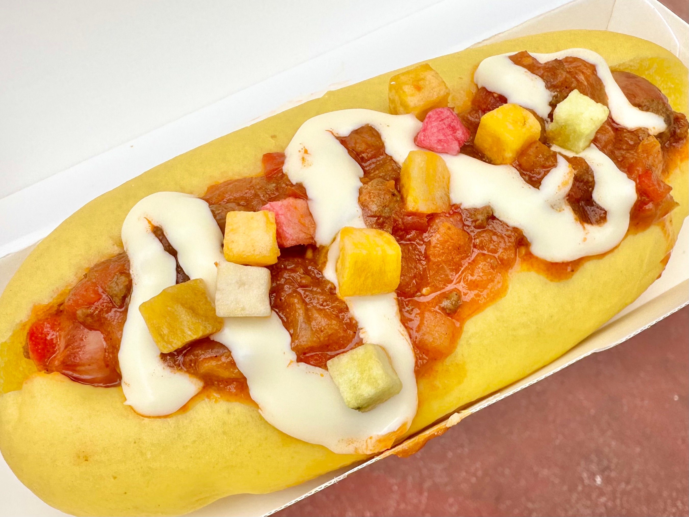 ホットドッグに具材が載っており、ソースとダイスカットされた野菜がかかっています。