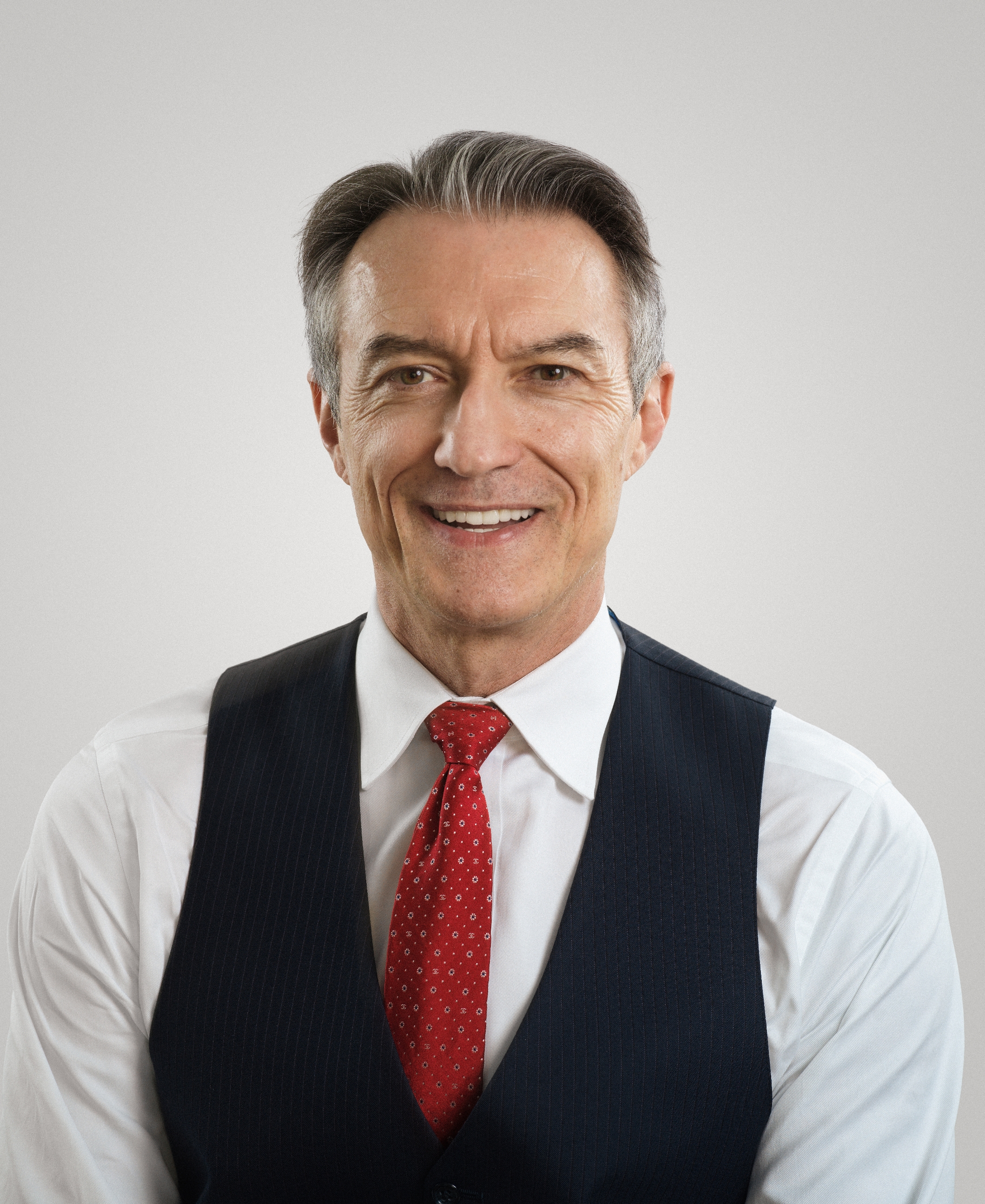 Smiling antheral   successful  a suit   with a achromatic  garment  and reddish  tie, looking straight  astatine  the camera