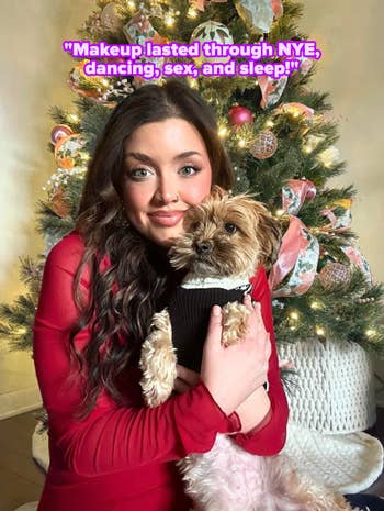 Person successful festive attire holding a canine successful beforehand of a decorated Christmas tree