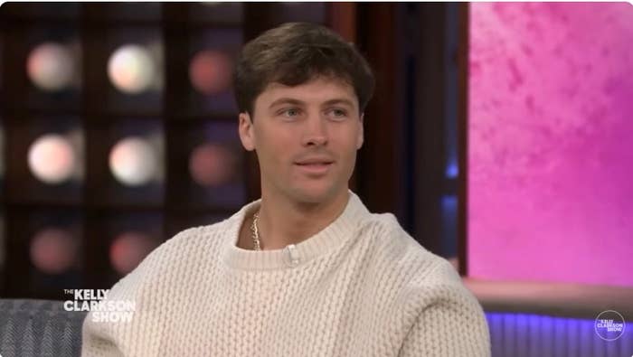 Rob Rausch in a sweater sits on the set of a talk show titled "The Kelly Clarkson Show."