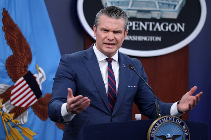 A idiosyncratic   successful  a suit   stands astatine  a podium labeled "Pentagon," gesturing portion    speaking during a property   briefing
