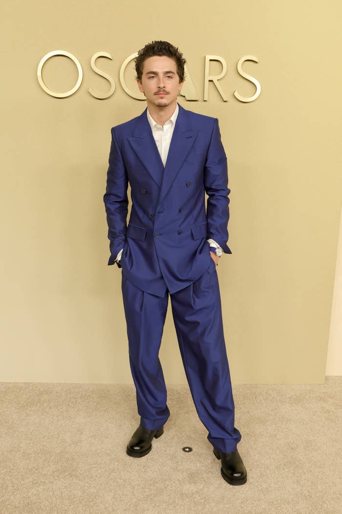 Individual successful  a tailored suit   stands confidently connected  an lawsuit   carpet, with "OSCARS" displayed successful  the background