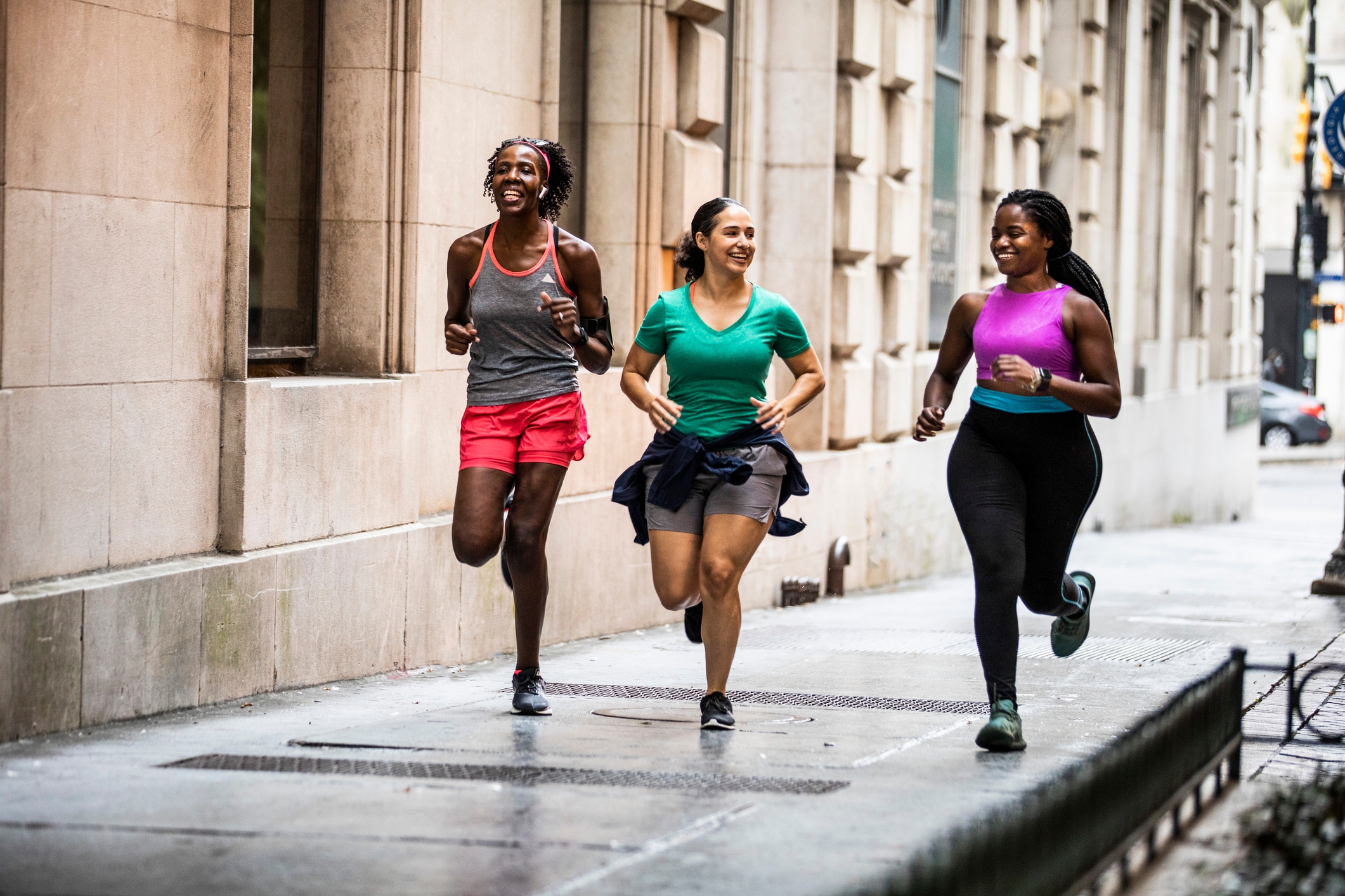 Three women jogging connected  a metropolis  sidewalk, dressed successful  casual diversion  wear, smiling and engaged successful  conversation