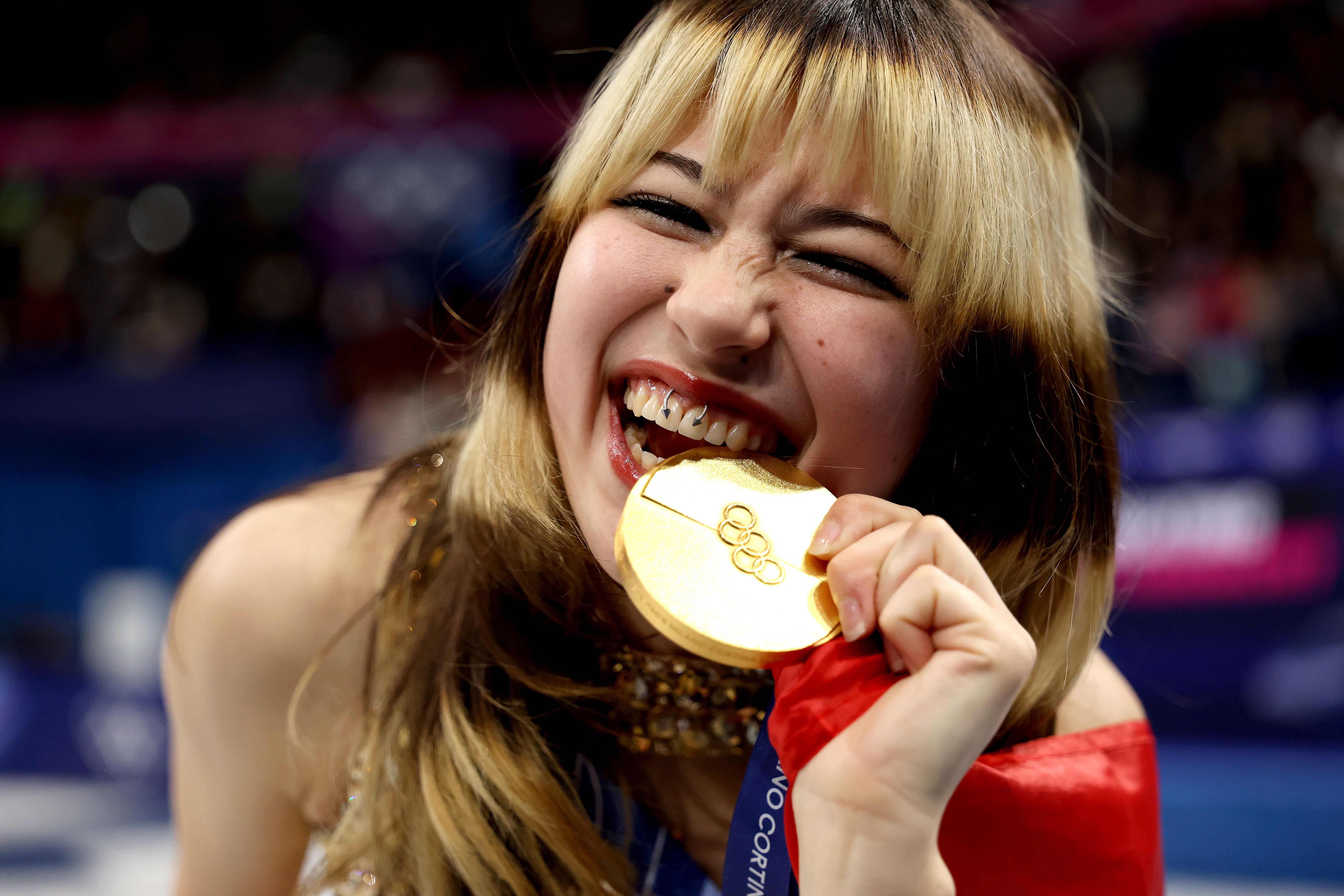 Person biting a golden  medal with a joyful expression, astatine  a sports event
