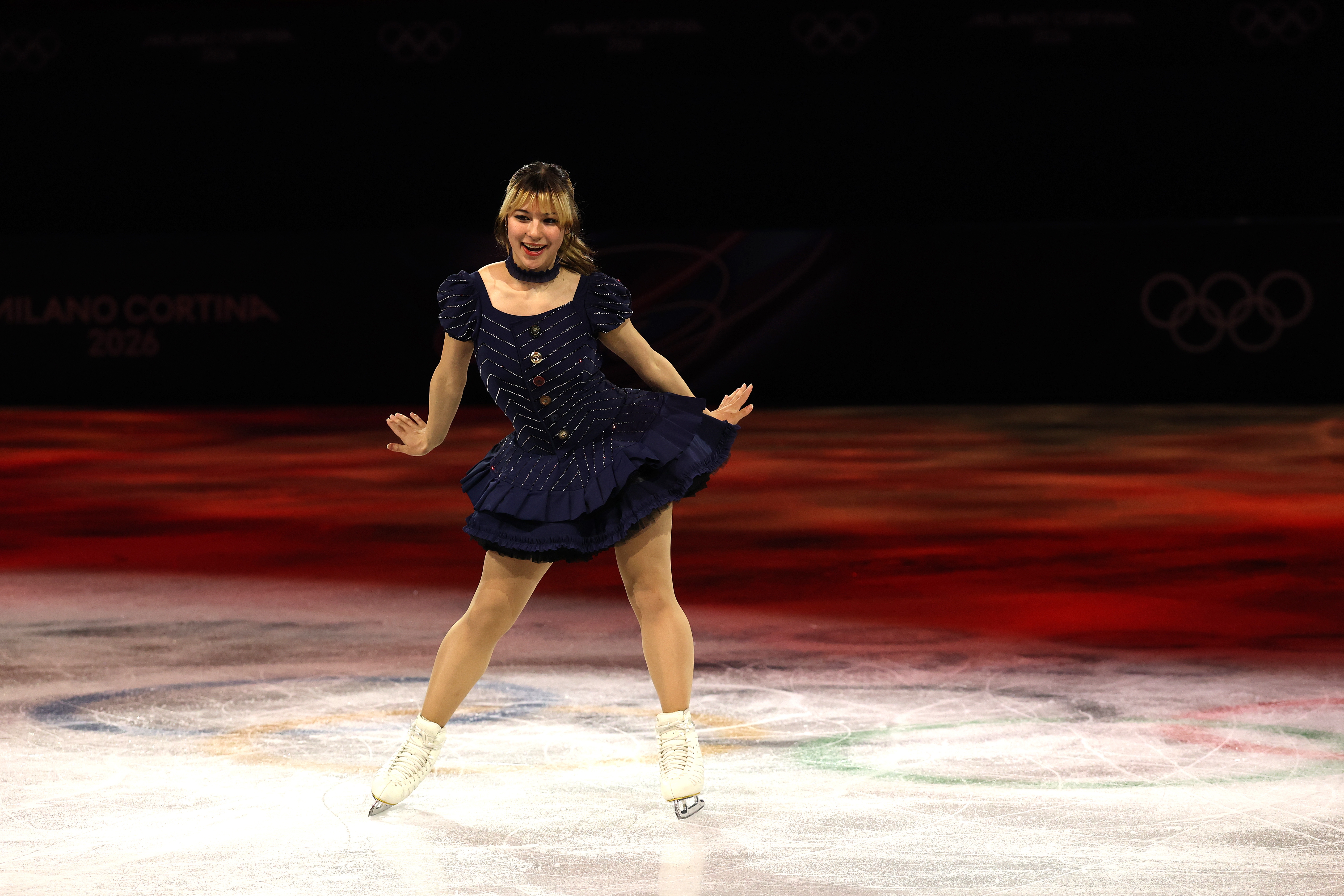 Figure skater performs connected  crystal  successful  a stylish, ruffled formal  during an event, showcasing elegance and artistry. Olympic rings disposable   successful  the background