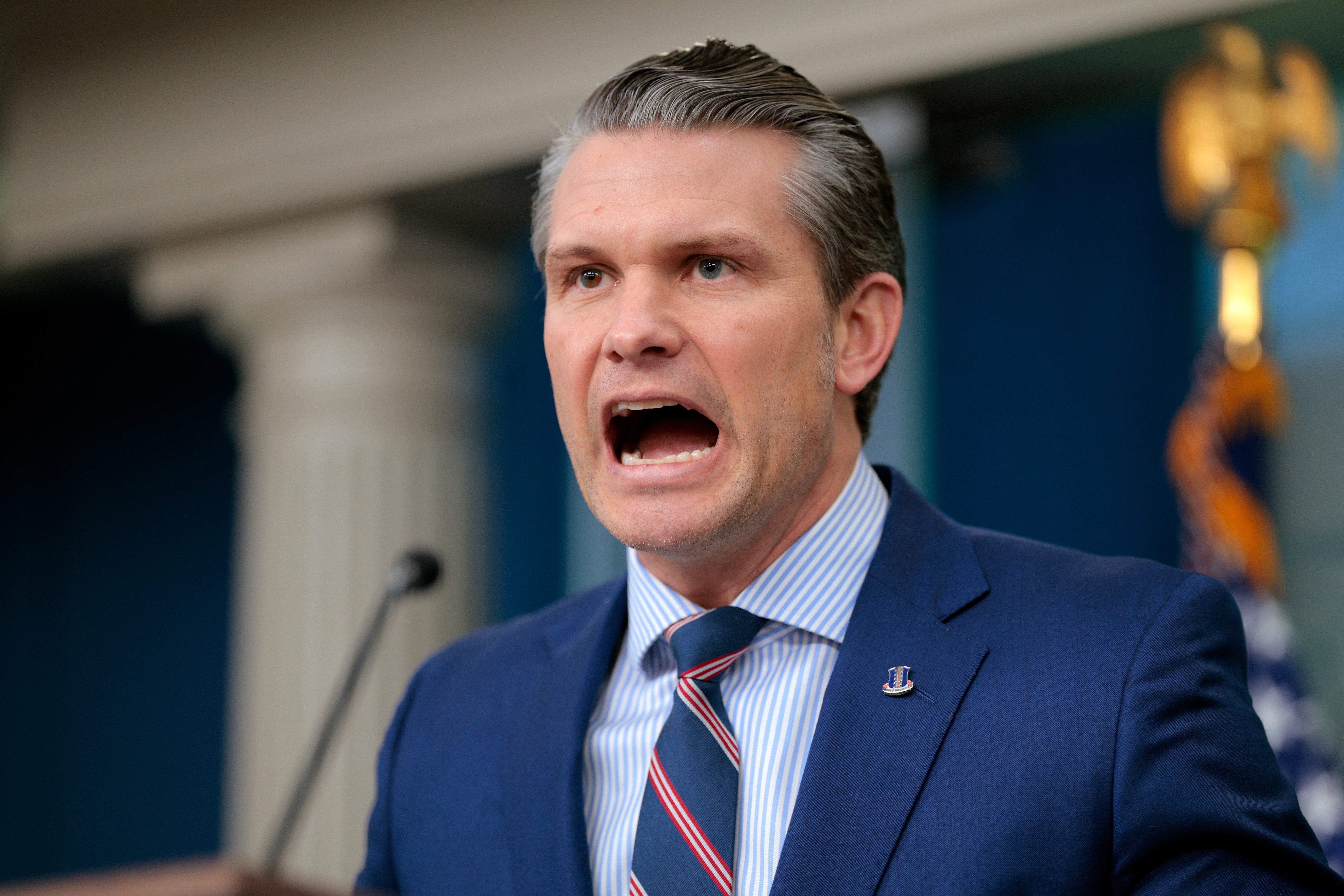 Pete Hegseth på et podium med åpen munn
