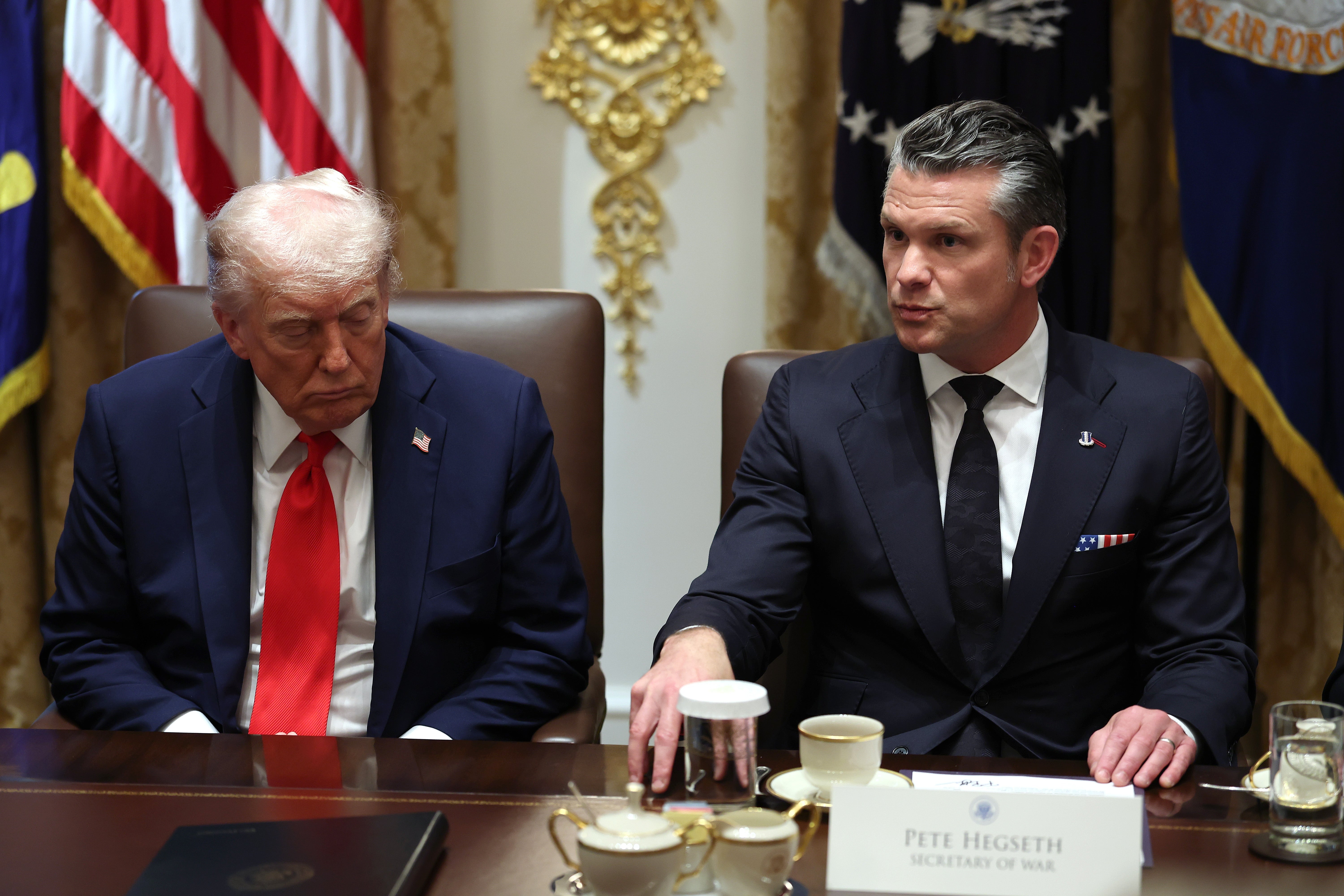 Donald Trump sitter ved siden av Pete Hegseth ved et bord; Pete gestikulerer mens han snakker og Trumps øyne er lukket og han lener seg nedover