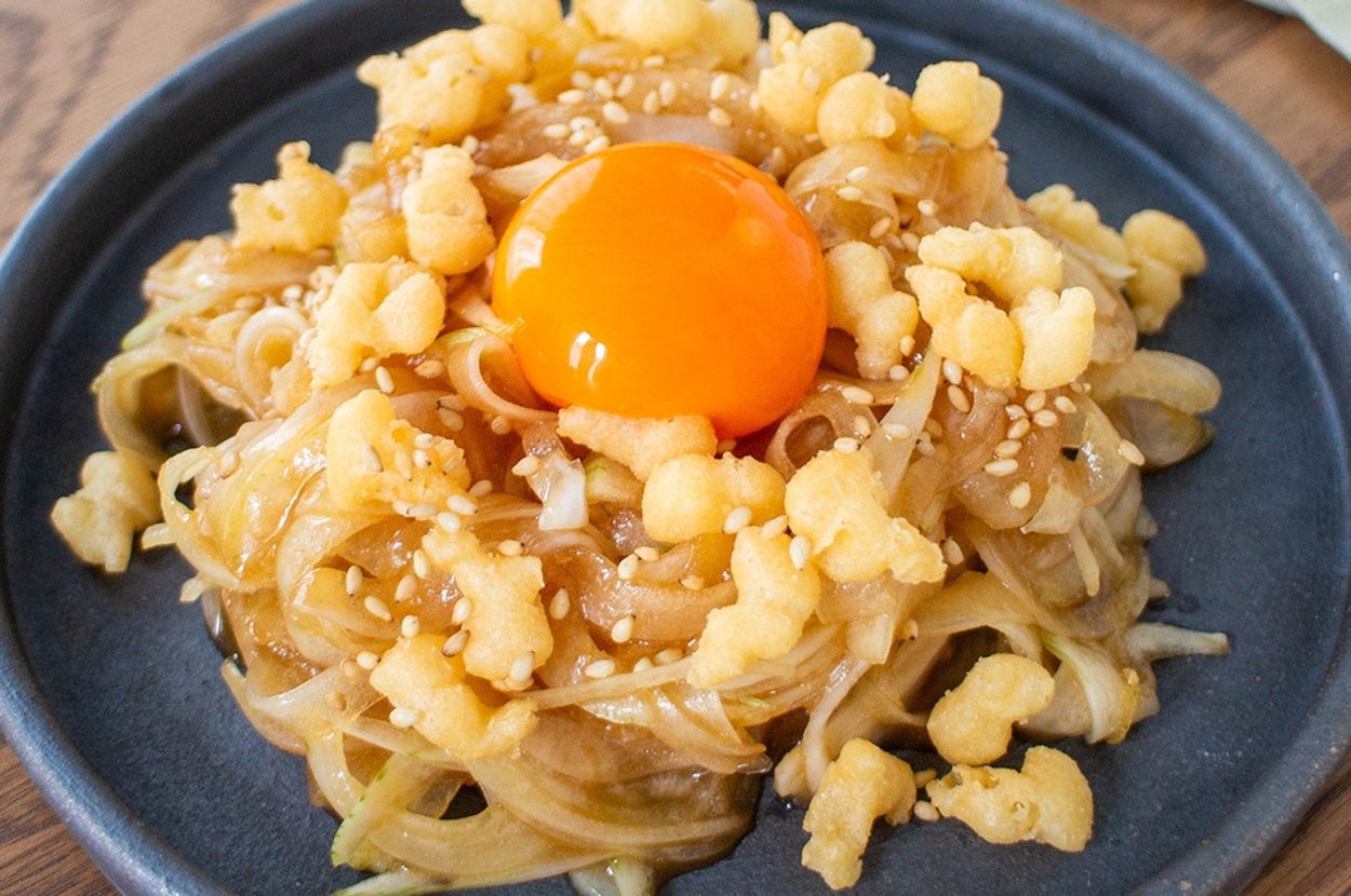 皿に盛られた黄身、生野菜、フライドトッピングの料理。美味しそうなビジュアル。