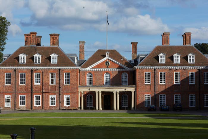 Historic ceramic  gathering  with aggregate  chimneys and arched windows, acceptable   against a cloudy sky, with a emblem  flying supra  the entrance
