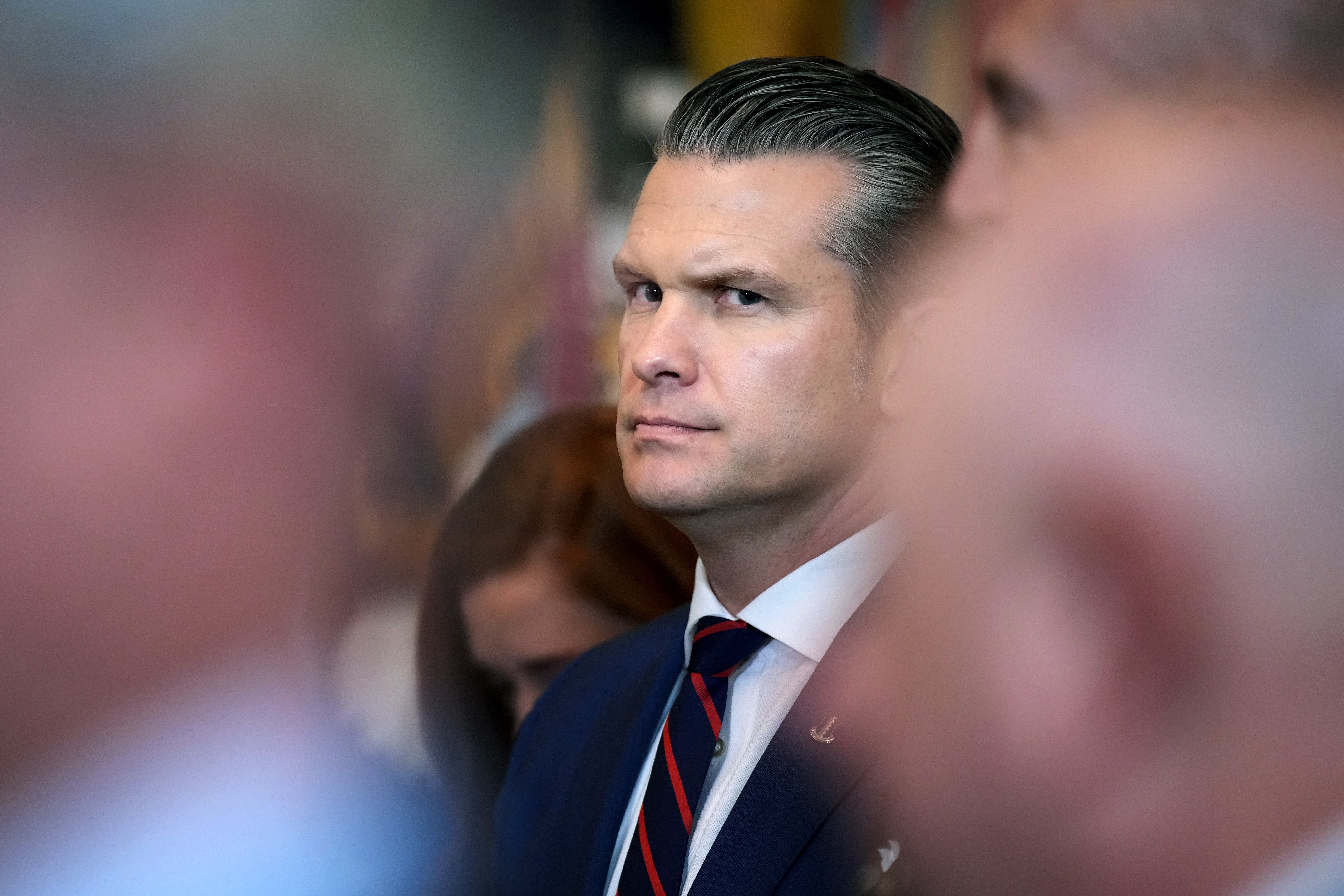 Pete Hegseth i dress med glatt hår midt i folkemengden, ser intenst til siden
