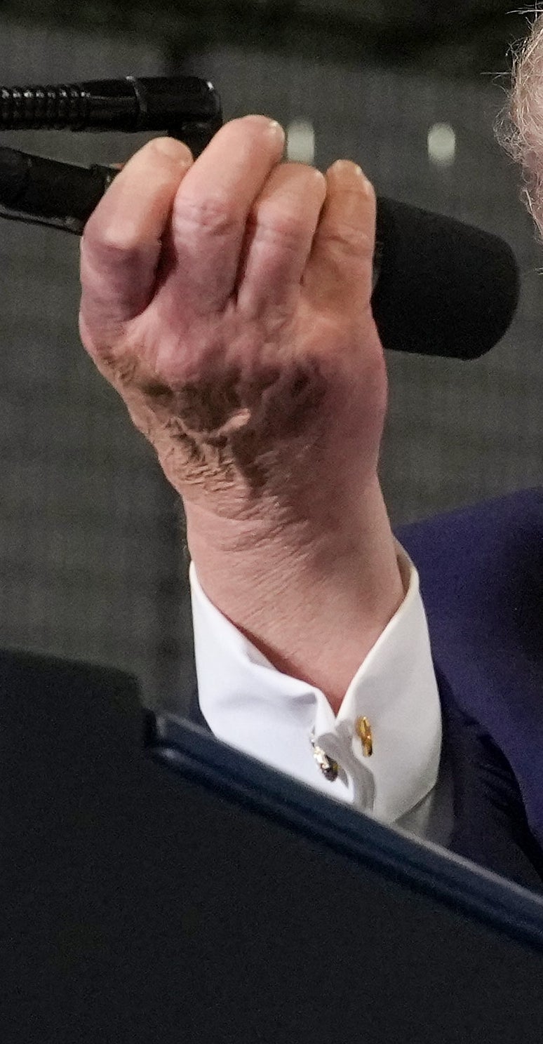 To personer står ved et podium, den ene iført dress og holder en mikrofon for den andre, som smiler i hvit topp og lett vest