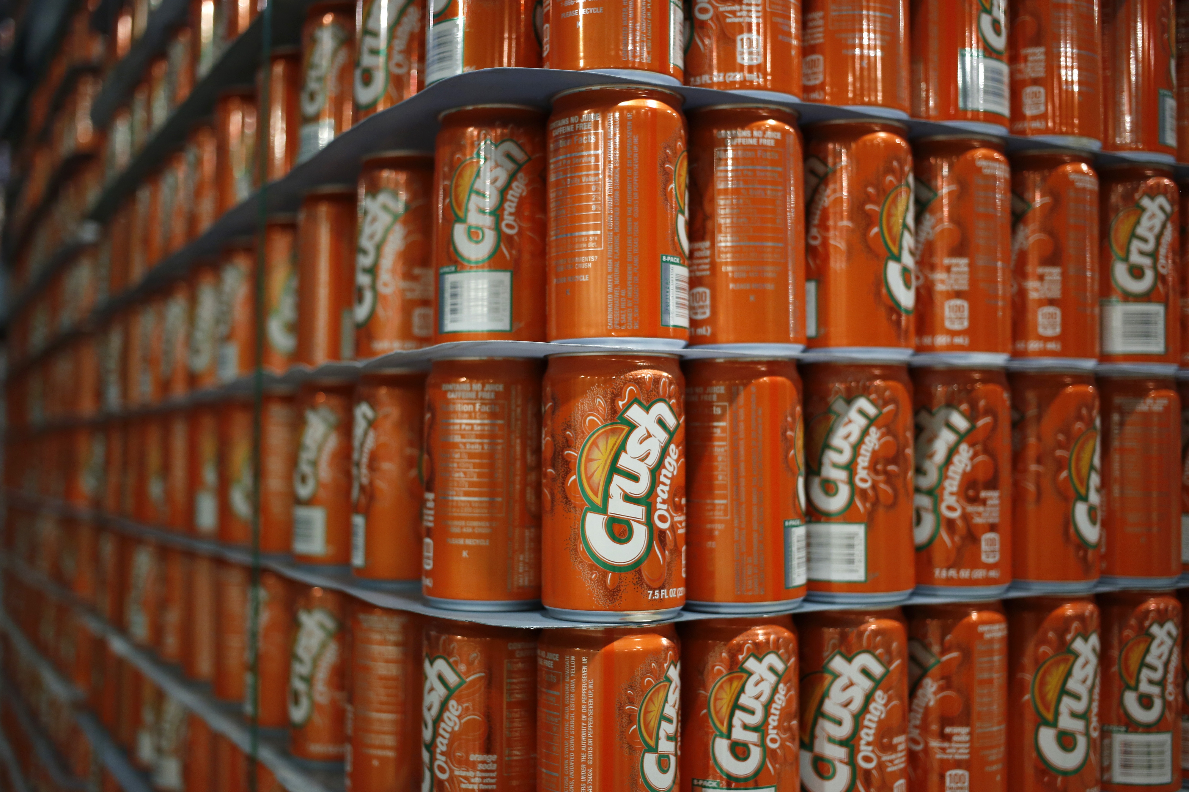 Stacks of orangish  Crush soda cans are lined up   connected  shelves successful  a store   display
