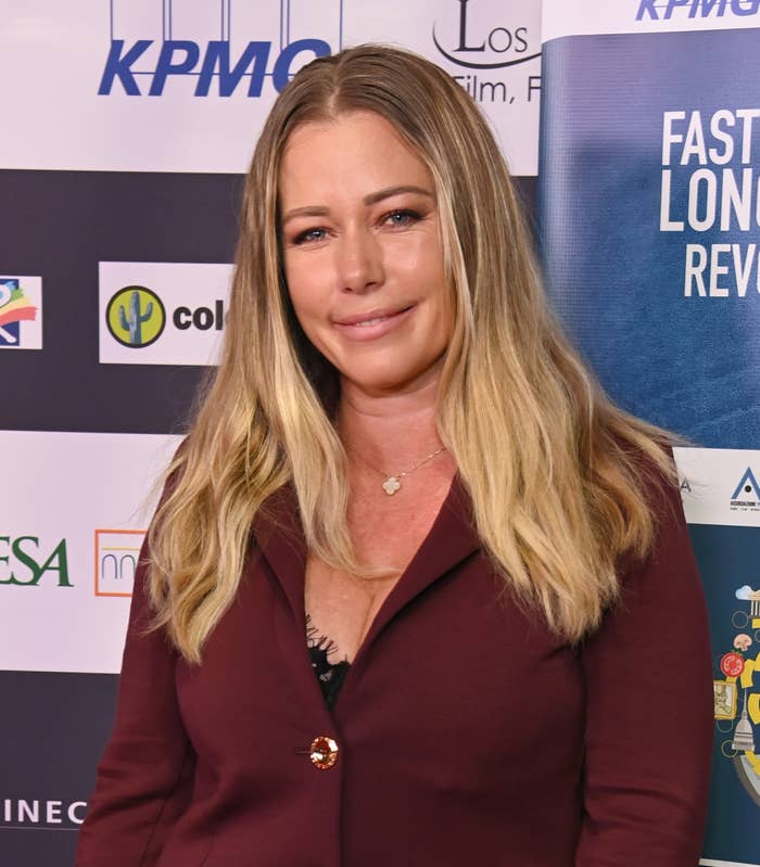 A idiosyncratic   connected  a reddish  carpet wearing a burgundy blazer implicit    a achromatic  top, lasting  successful  beforehand   of a backdrop with logos