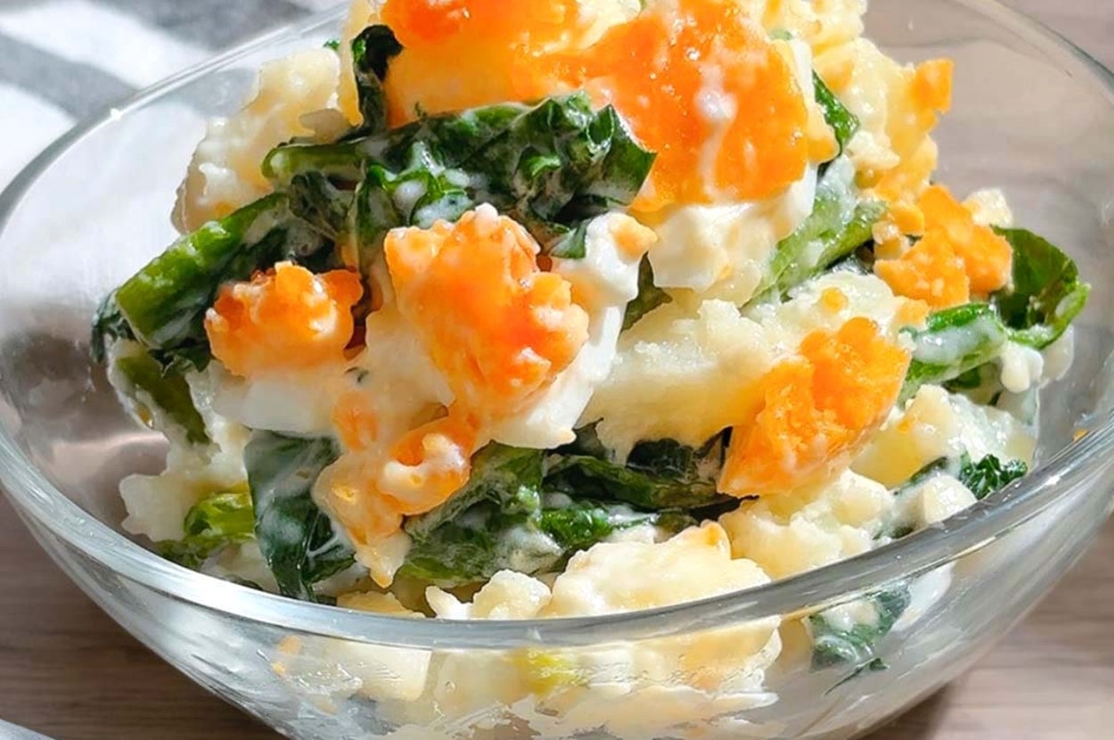 ガラスのボウルに入ったカラフルなポテトサラダ。ジャガイモ、葉野菜、ニンジンが見える。