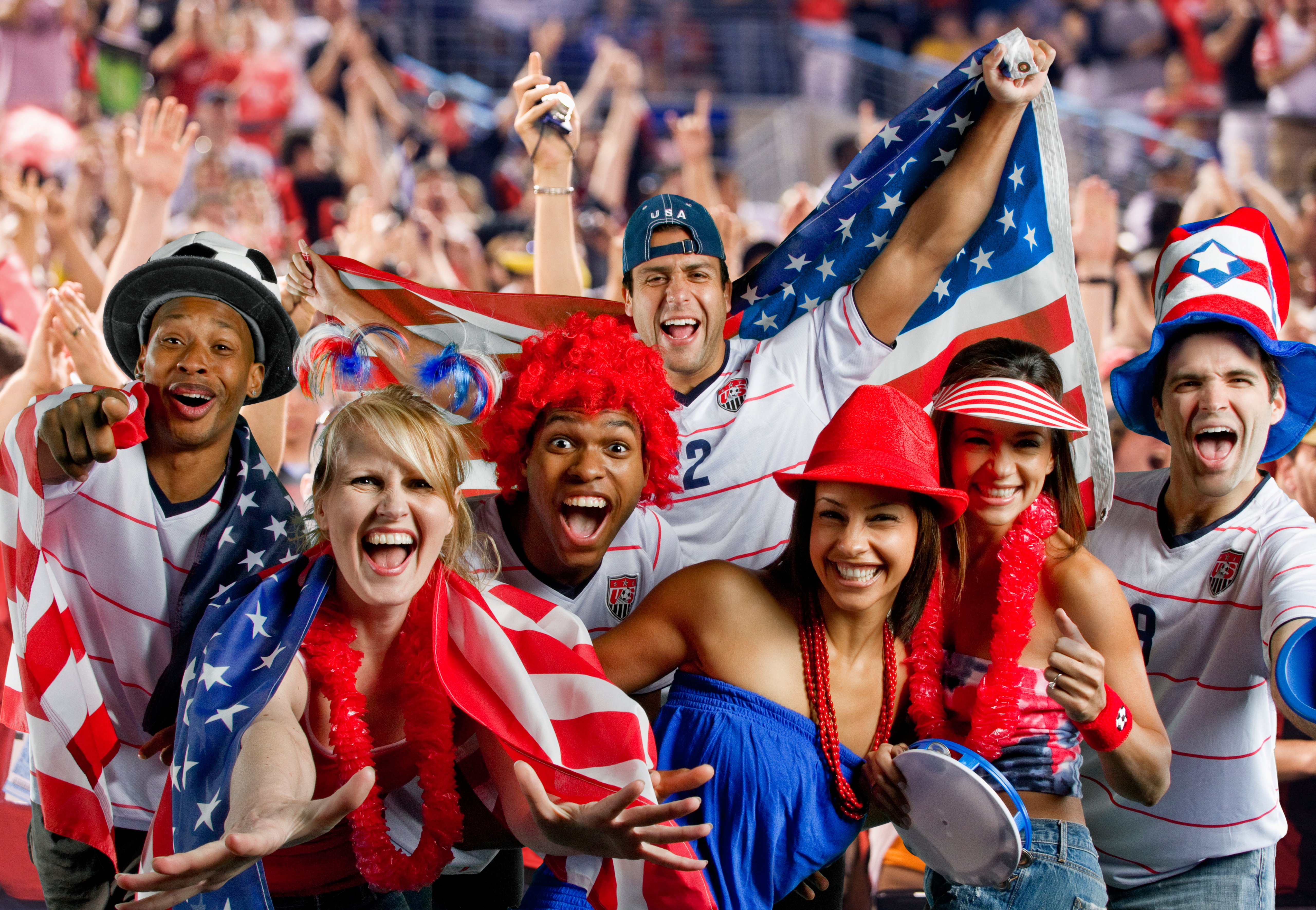 People astatine  a sports event, wearing festive accessories and holding American flags, look  excited and joyous, celebrating unneurotic  successful  a vibrant crowd