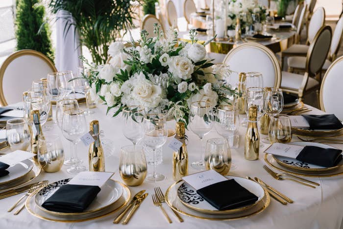 Elegant wedding reception array  acceptable   with golden  accents, achromatic  floral centerpiece, and personalized menus