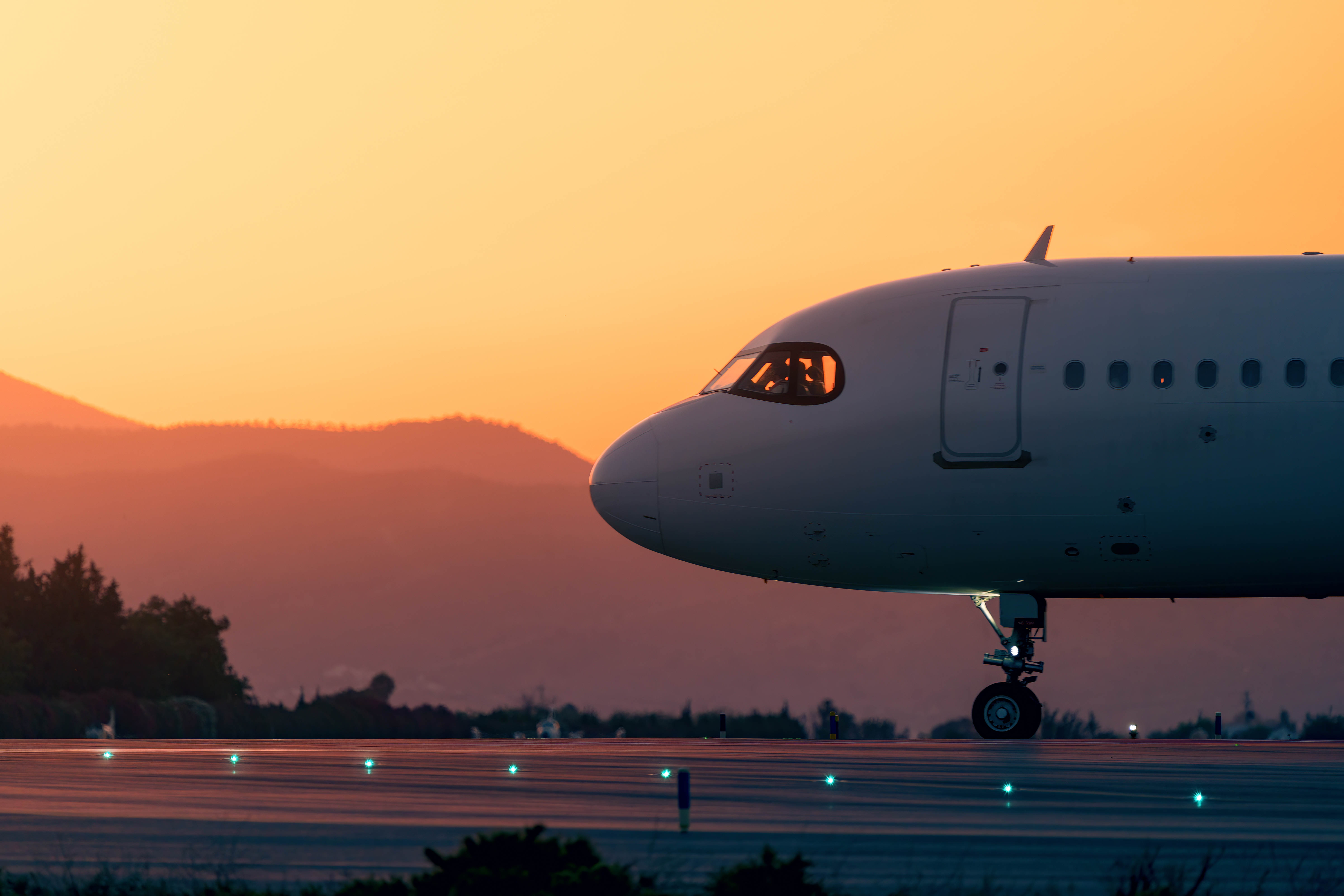 Airplane taxiing connected  a runway astatine  sunset with mountainous scenery  successful  the background