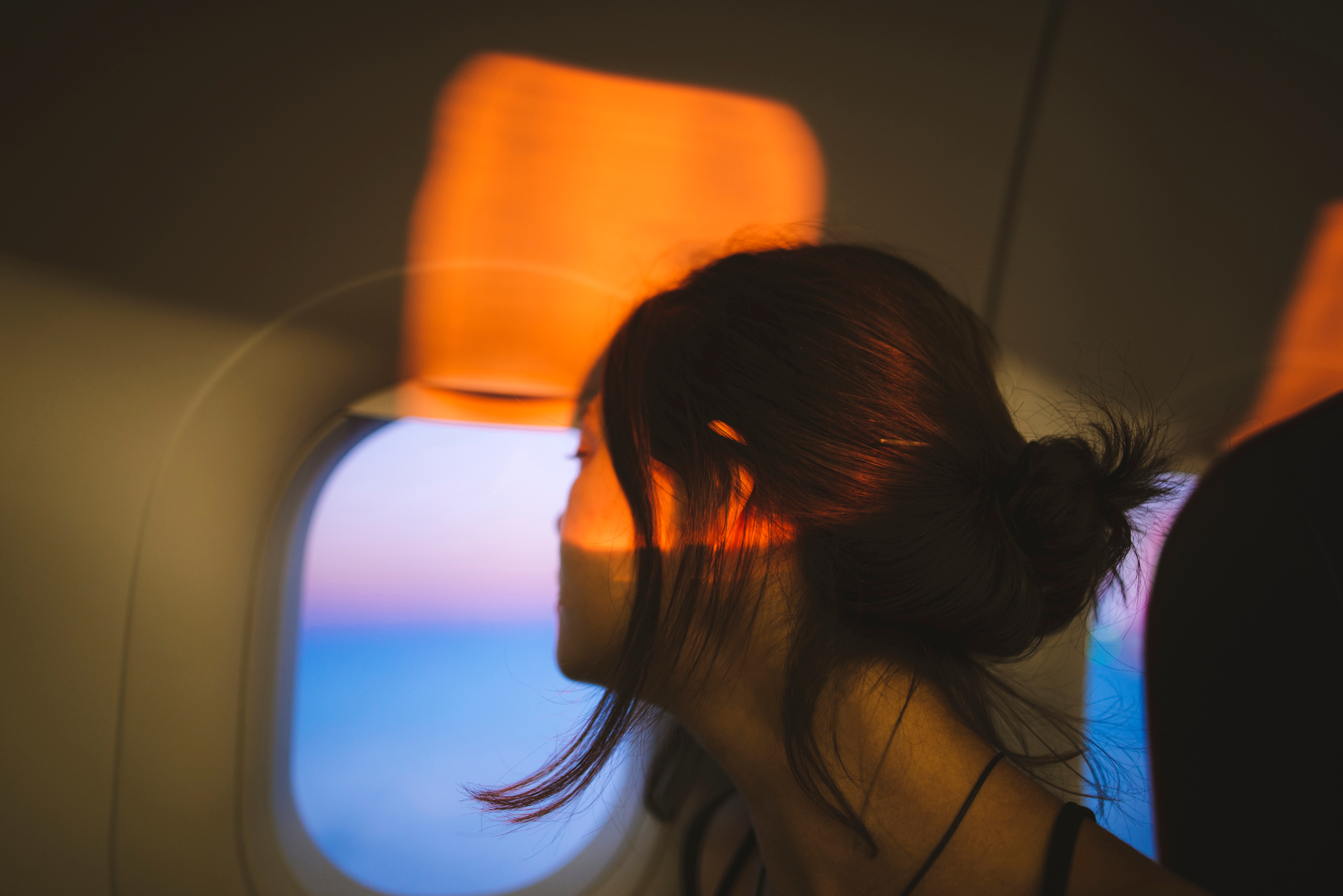Person gazes retired  an airplane window, looking thoughtful. Warm airy  casts dynamic patterns connected  their face, adding an creator  effect   to the scene