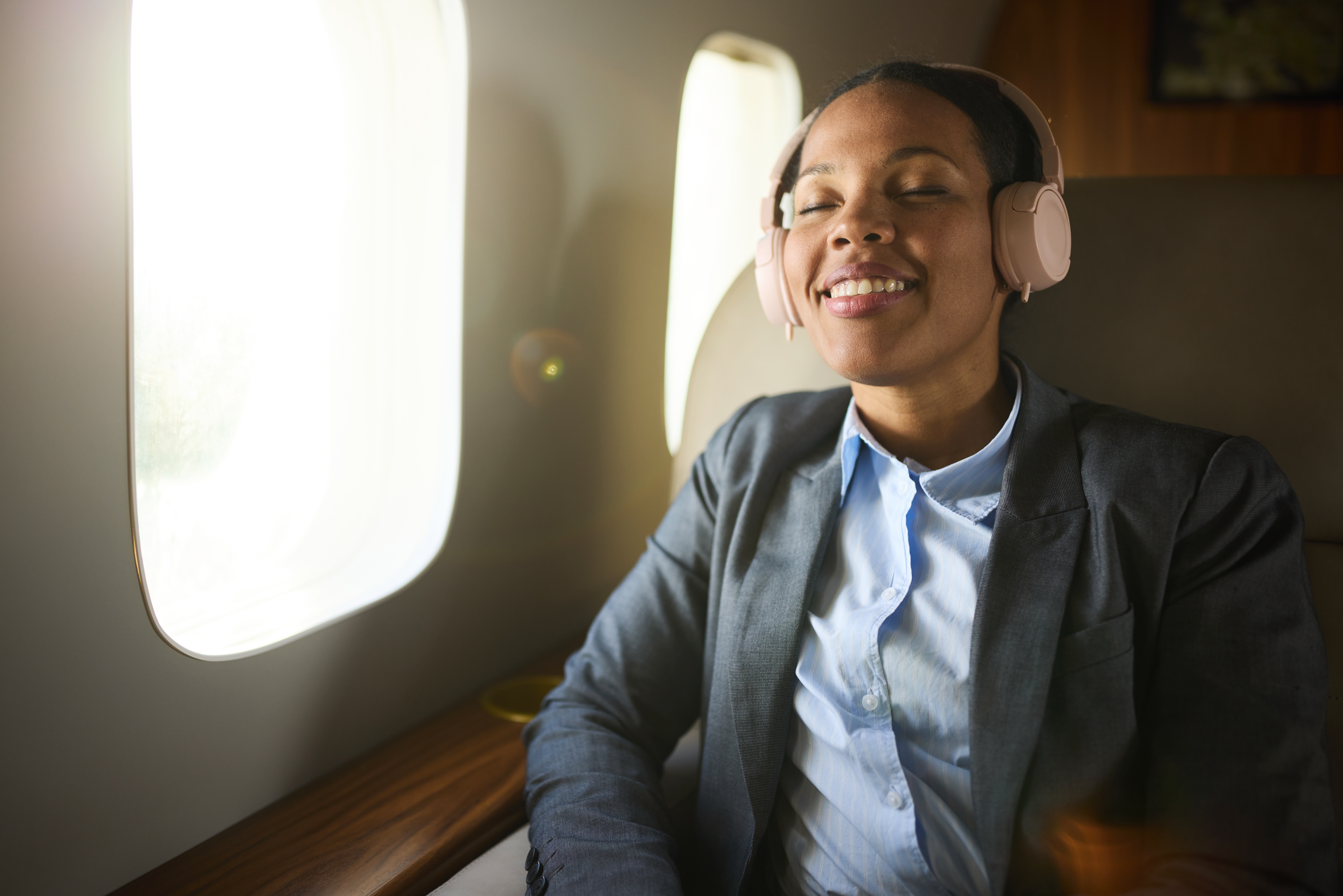 Person successful  a suit   and headphones sitting successful  an airplane seat, smiling with eyes closed