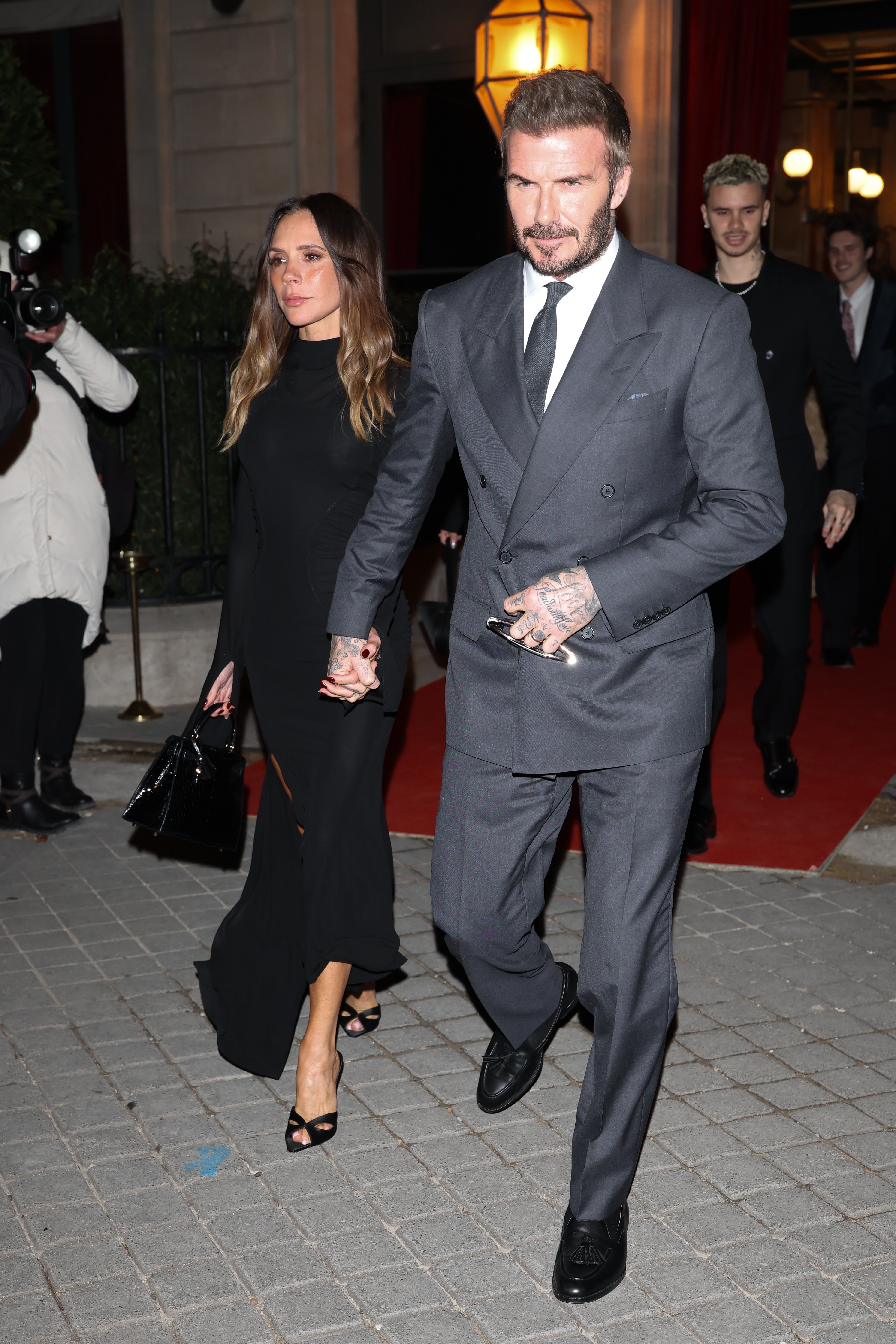Victoria and David Beckham locomotion hand-in-hand distant from a reddish carpet