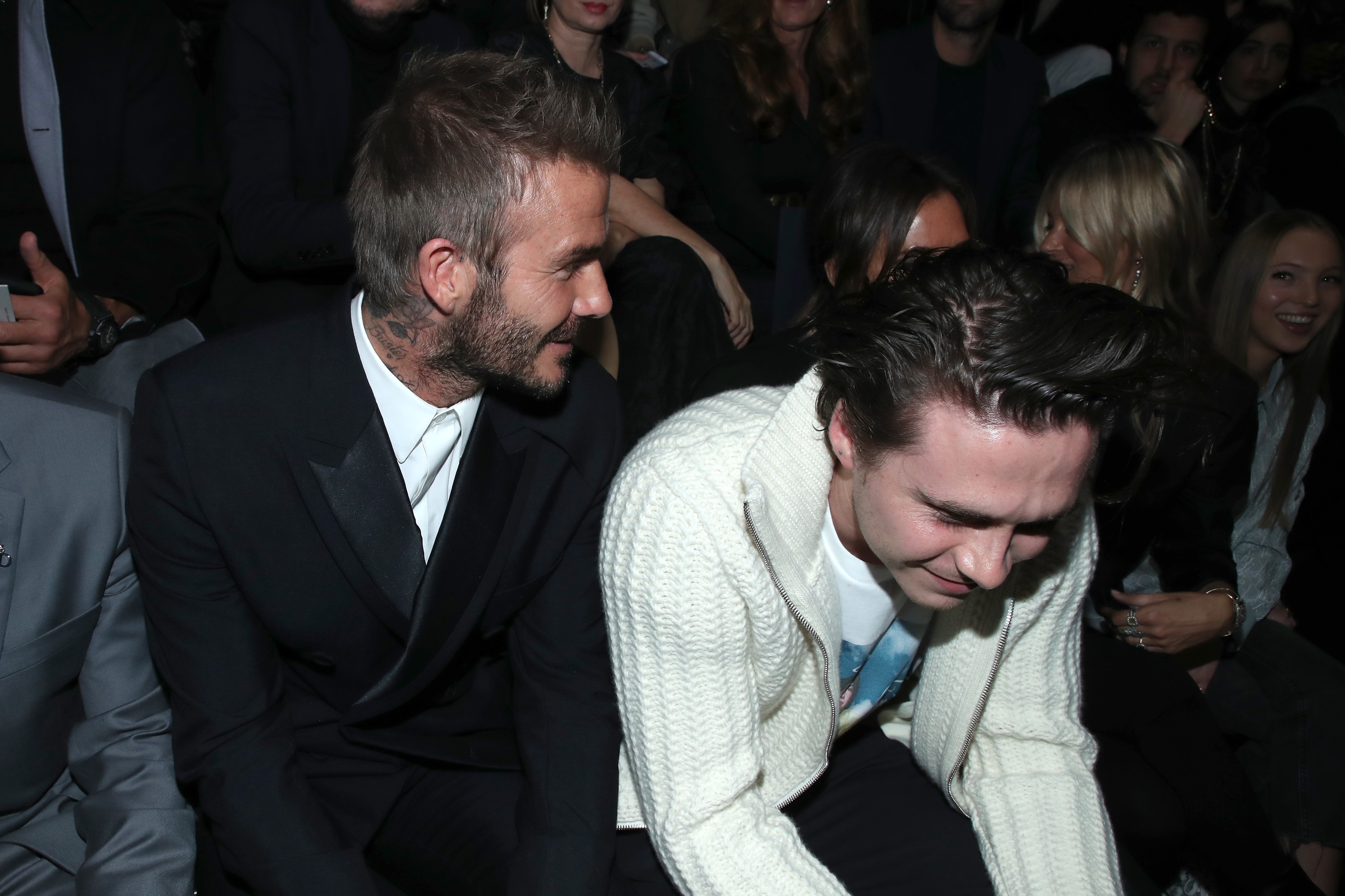 David and Brooklyn Beckham seated astatine an event, some smiling and engaging with each other