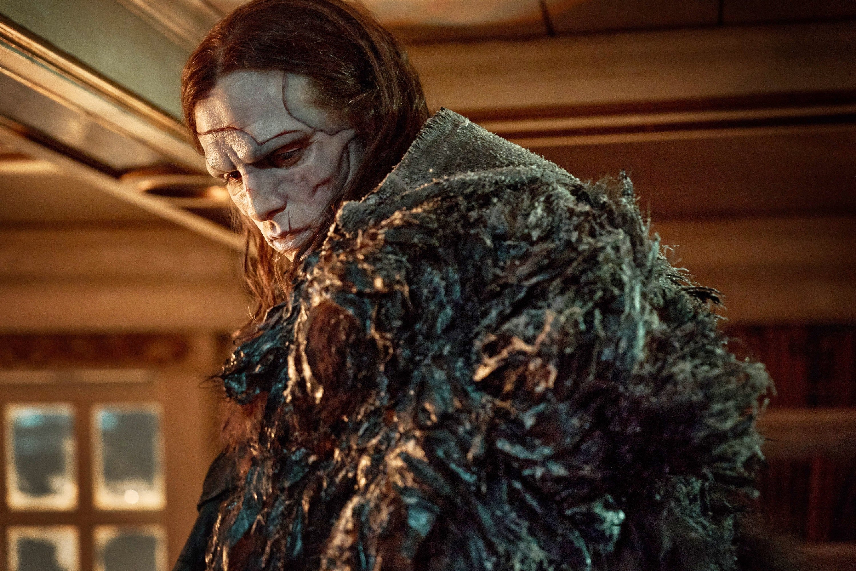 En mystisk figur i et detaljert kostyme med et dystert uttrykk, satt i et svakt opplyst rom, som fremkaller en mørk og gåtefull atmosfære