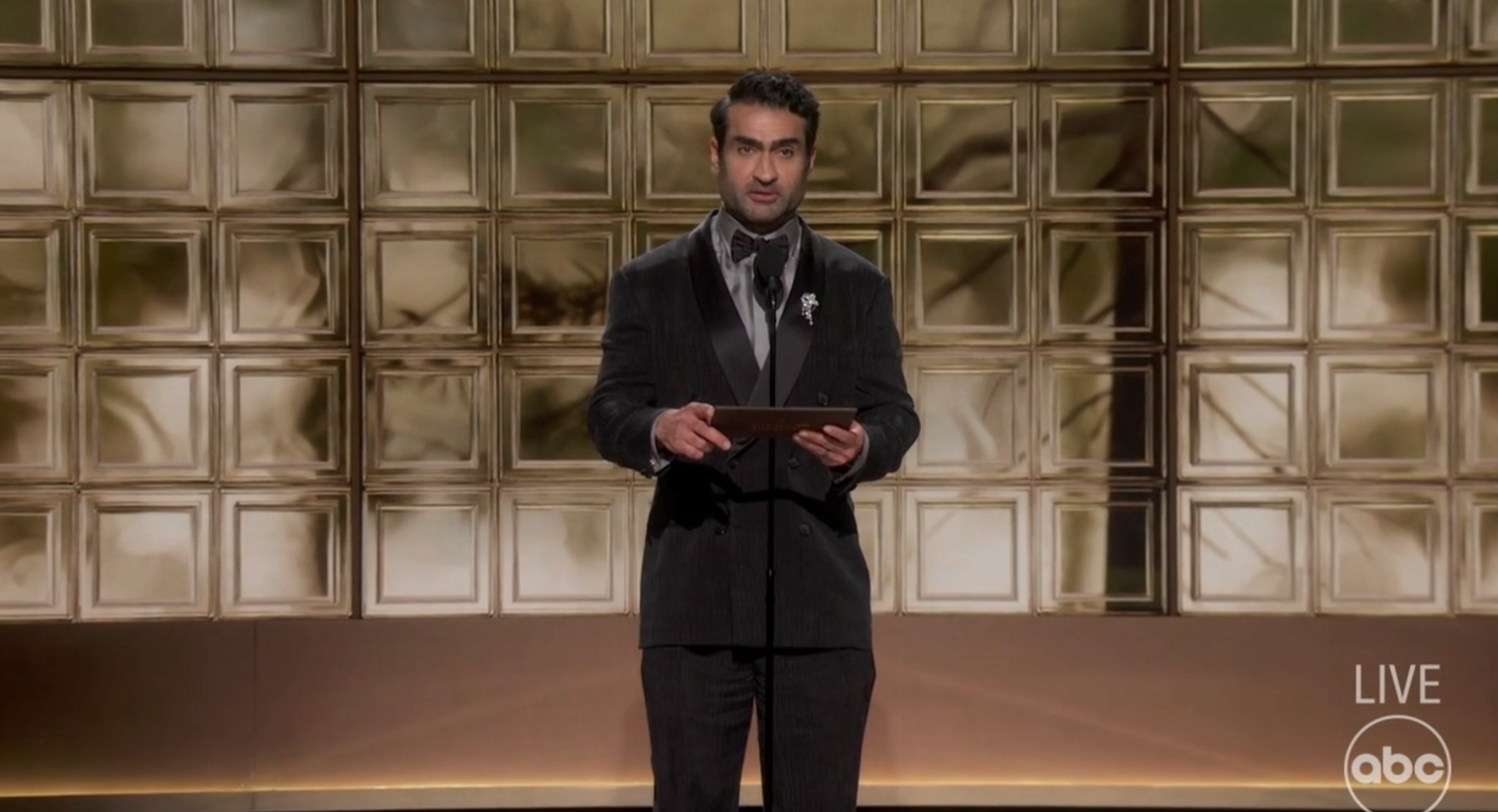 Person successful ceremonial achromatic suit connected signifier presenting astatine an event. Geometric backdrop