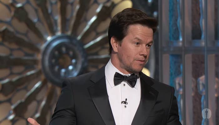 A idiosyncratic   successful  a tuxedo is speaking astatine  a ceremonial  event, lasting  successful  beforehand   of a decorative backdrop