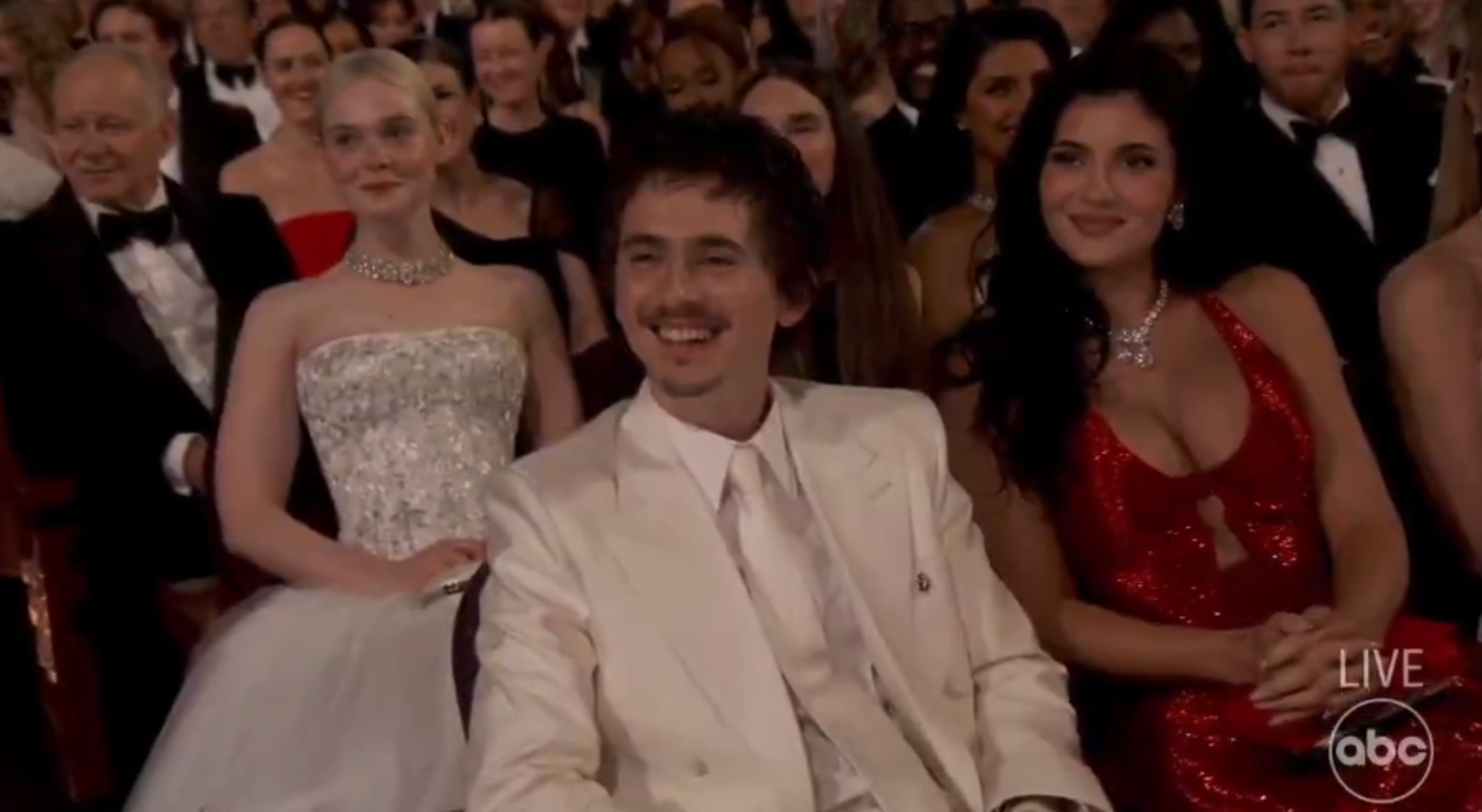 Timmy smiles and laughs awkwardly, kylie Jenner beside him smiles tightly