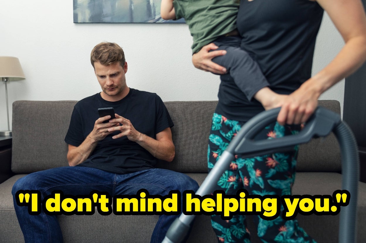 Man sits on couch absorbed in phone while another stands nearby vacuuming with a child. Text: "I don't mind helping you."