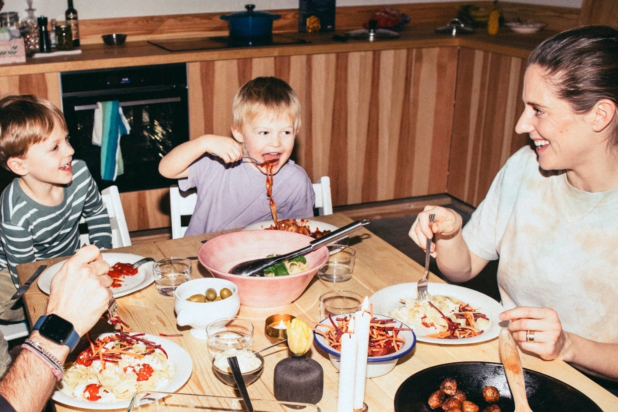 Family enjoying a meal together at a dining table with laughing children and an adult