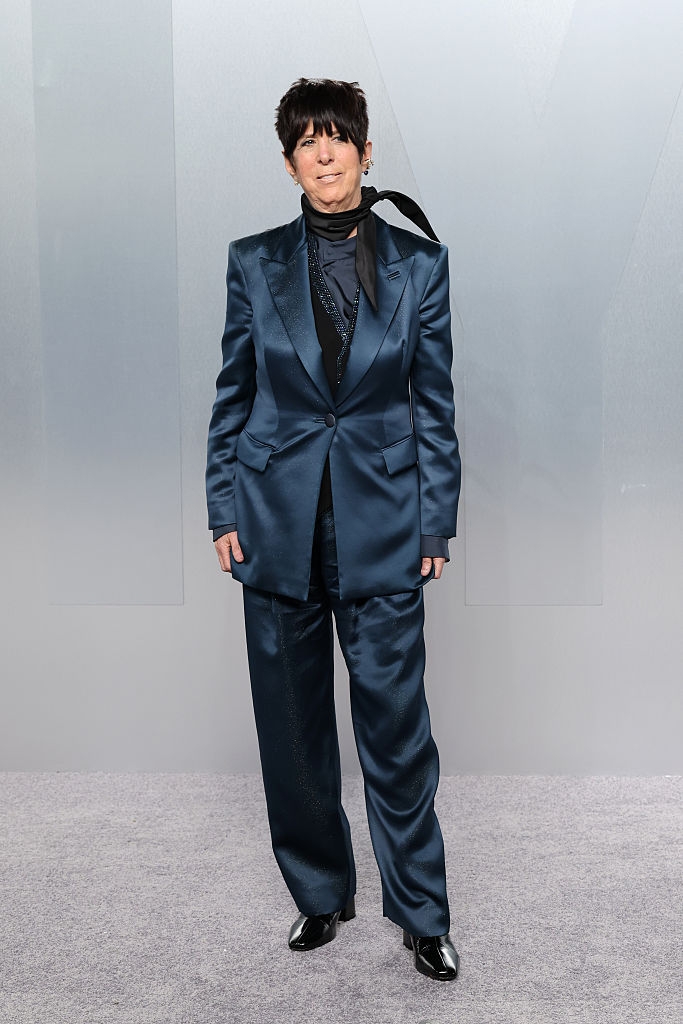 Person successful a sharp, tailored suit, lasting connected a carpet. The outfit includes a jacket, shirt, pants, and boots