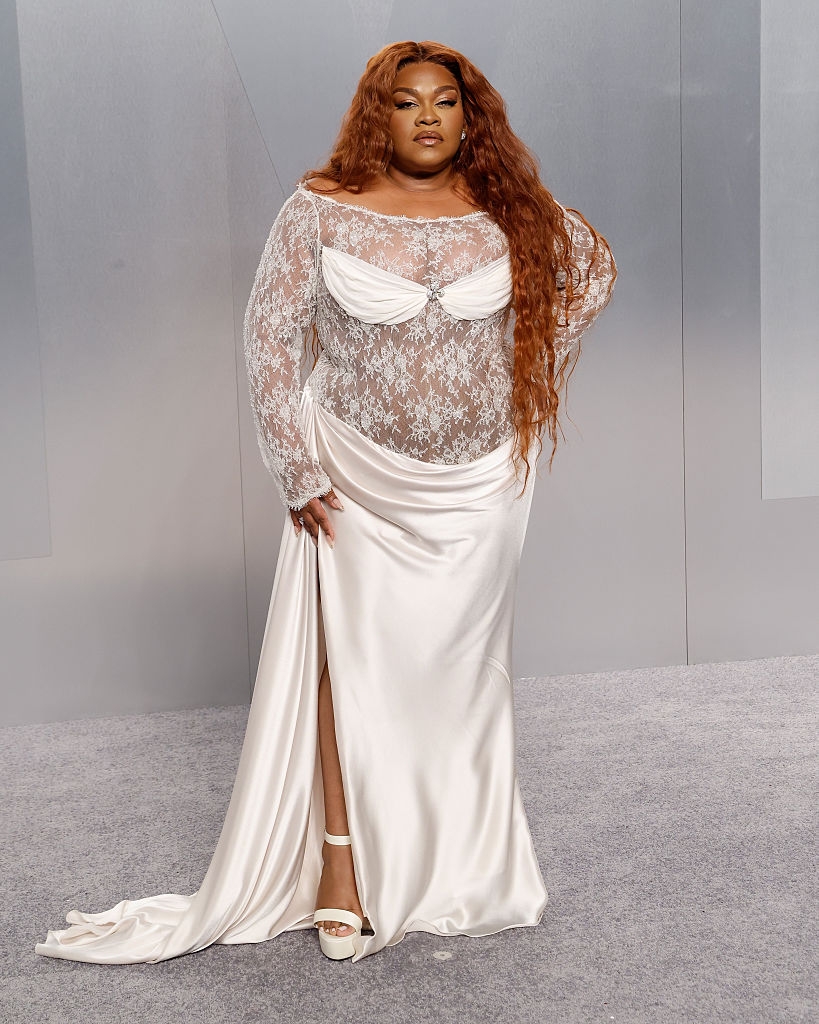 Person successful sheer lace apical and satin skirt poses confidently connected neutral backdrop, successful a benignant often seen astatine high-profile events