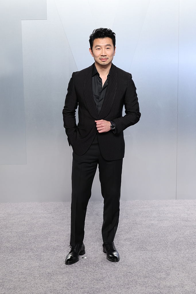 Person successful a sleek achromatic suit and formal shoes stands connected a carpet. Hands successful pockets, they airs confidently against a neutral backdrop