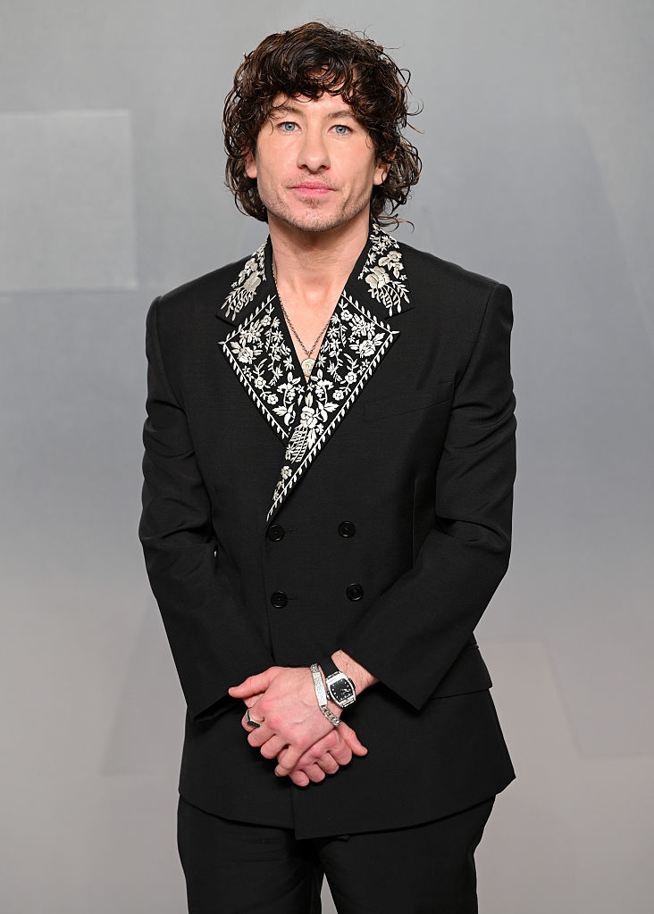 Public fig successful a tailored achromatic suit with intricate floral embroidery connected the lapel, posing connected a plain backdrop