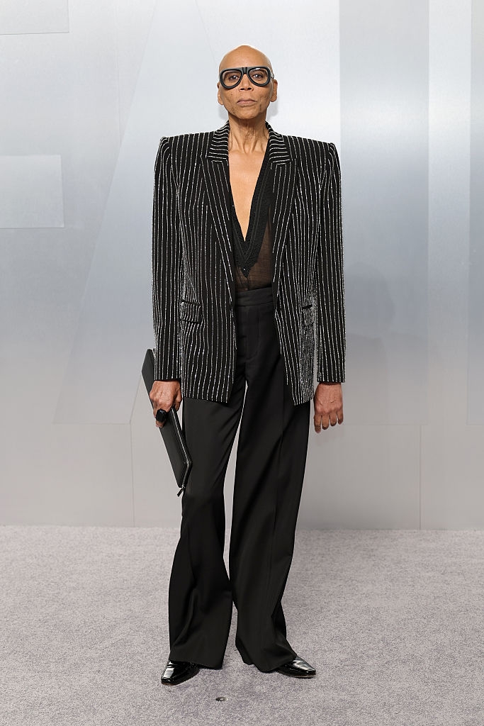 Person successful a pinstripe suit with a heavy V-neck, holding a clutch, lasting connected what appears to beryllium a reddish carpet