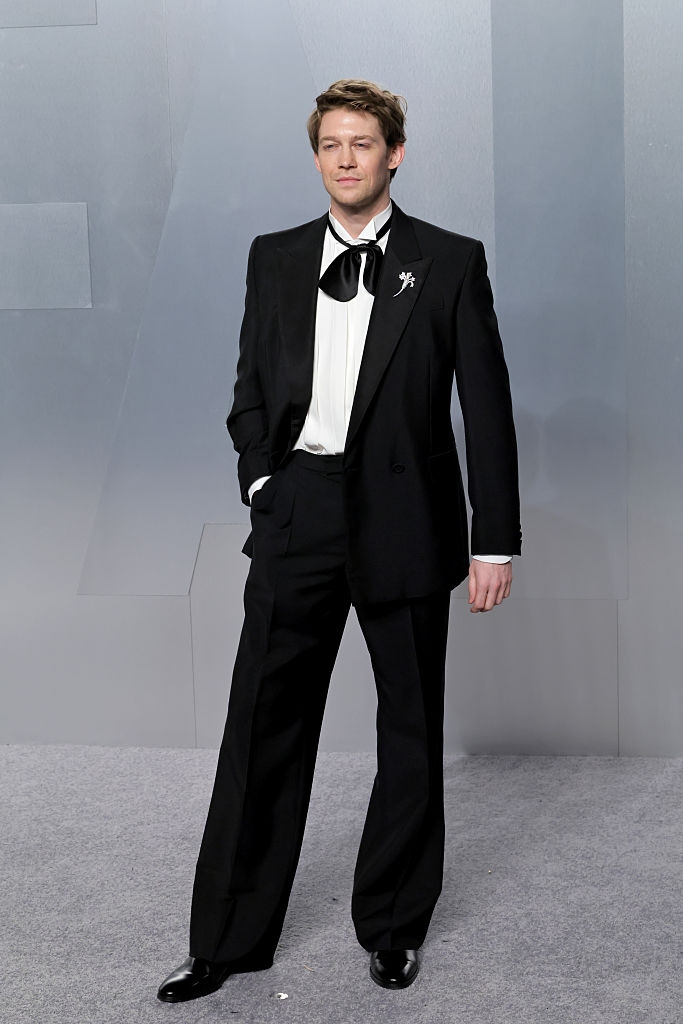 Person successful a ceremonial suit with a bow, posing connected a carpet