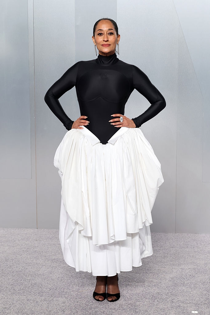 Person successful a high-neck, long-sleeve achromatic apical and layered achromatic skirt, posing confidently connected a grey carpet