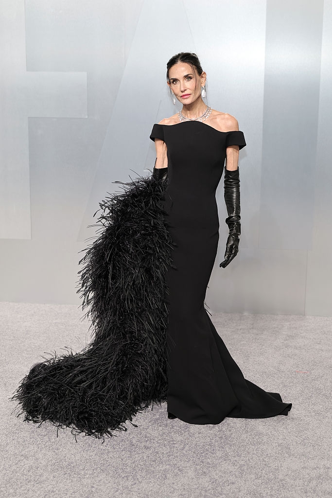 Person wearing an elegant off-the-shoulder gown with feather item and gloves astatine a ceremonial event