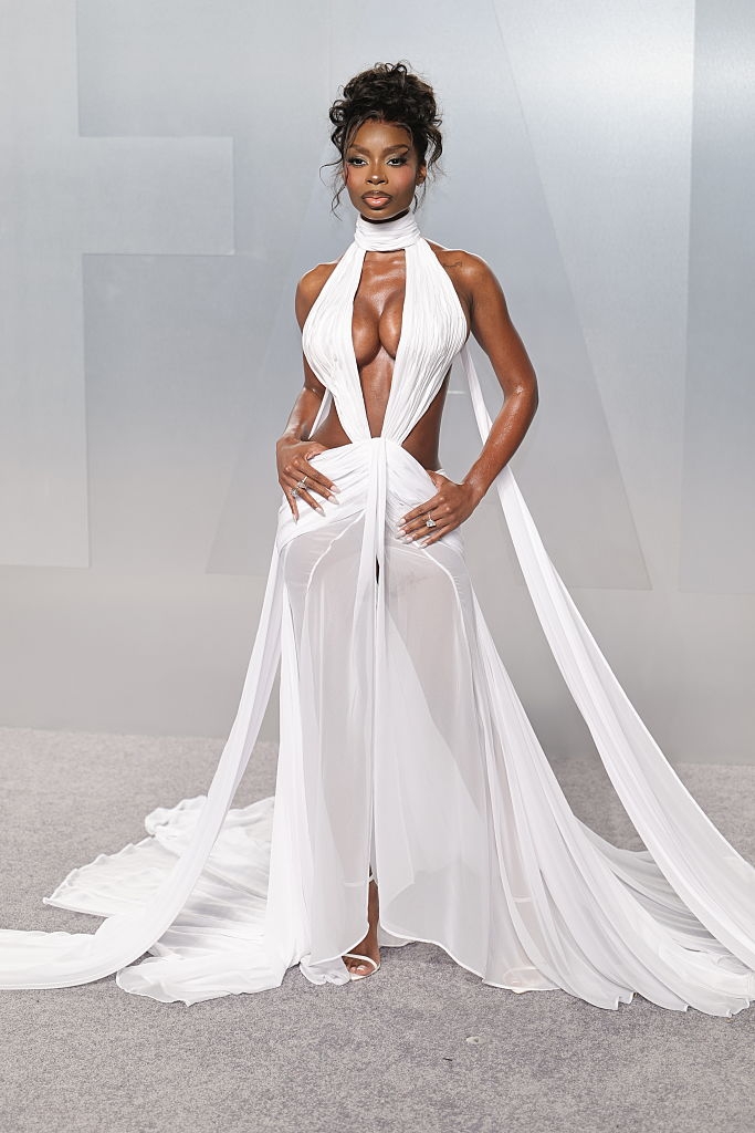 Person successful an elegant, flowing achromatic gown connected a reddish carpet, featuring bold cutouts and a halter neckline