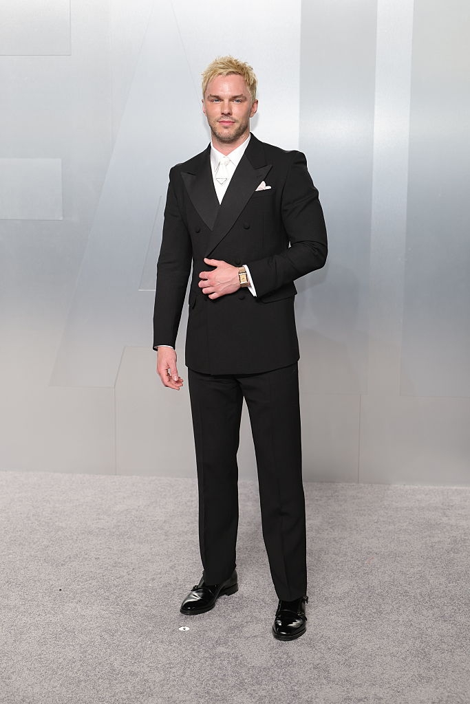 Man successful a tailored achromatic double-breasted suit with a achromatic garment and necktie connected a reddish carpet