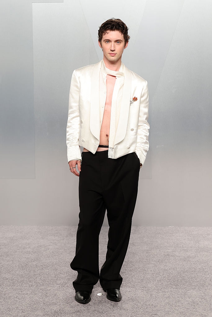 Individual successful a achromatic unfastened overgarment and achromatic pants stands connected a reddish carpet