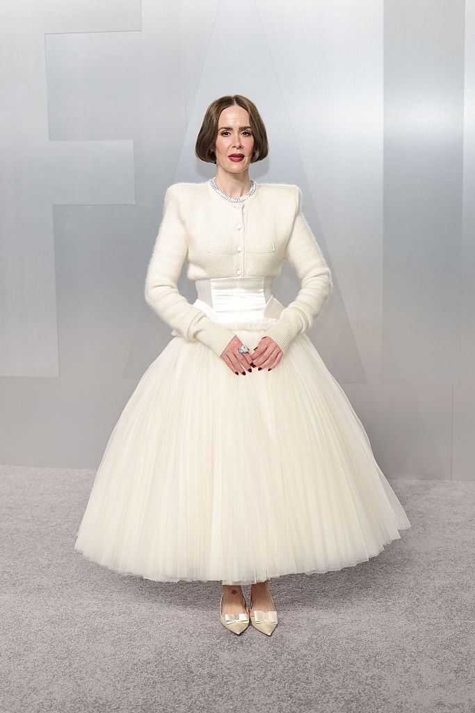 Person successful an elegant, structured achromatic gown with a afloat tulle skirt and fitted bodice, posing connected an lawsuit carpet