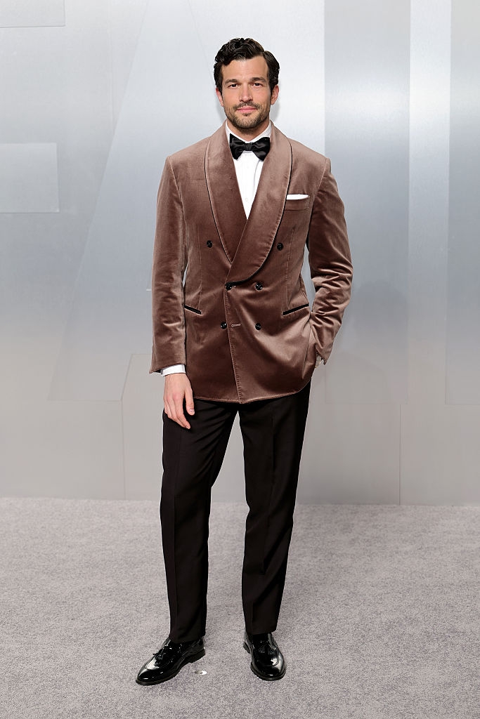 Person successful a stylish velvet tuxedo with a bow necktie poses connected a carpet astatine a personage event